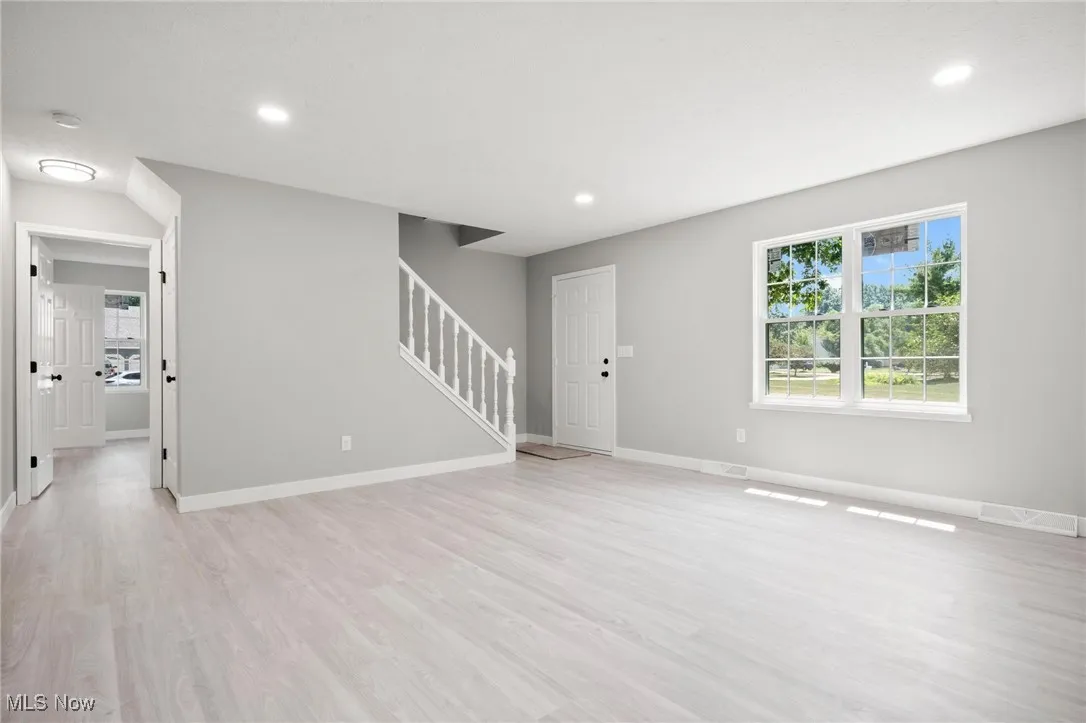 Unfurnished living room with stairway, light wood-style floors, and recessed lighting