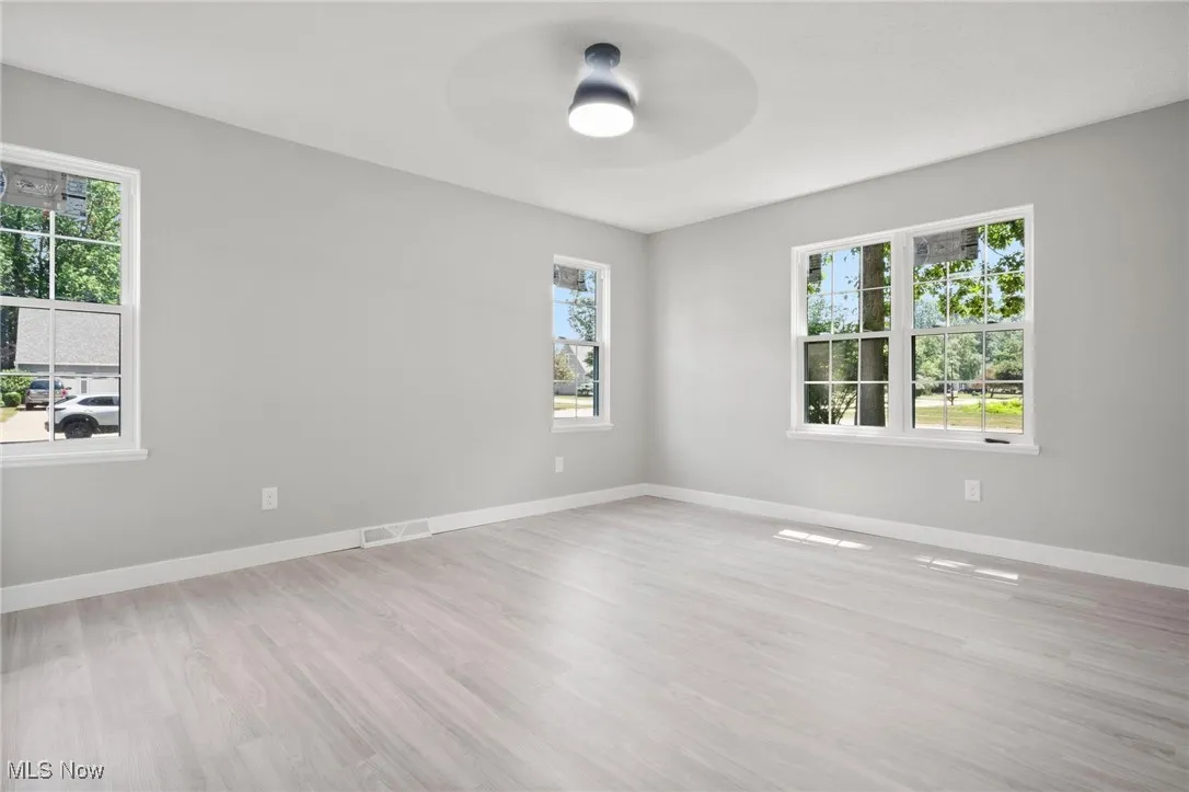 Spare room featuring a ceiling fan, healthy amount of natural light, and wood finished floors
