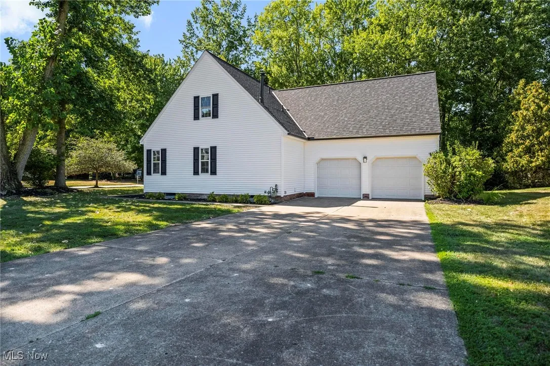 View of front of home with a garage, concrete driveway, a front yard, and a shingled roof