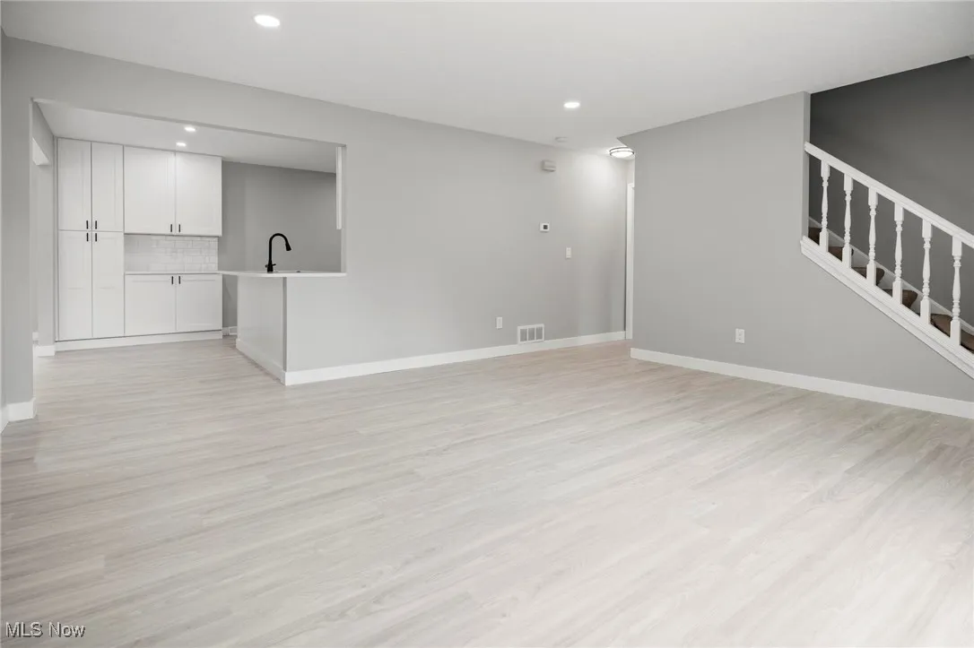 Unfurnished living room featuring light wood finished floors, stairs, and recessed lighting