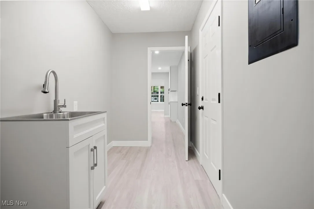Corridor featuring light wood-style flooring, electric panel, and a textured ceiling