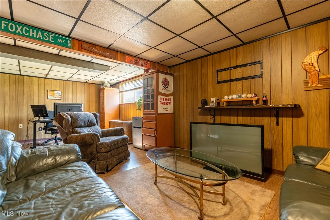 Living area featuring a paneled ceiling, wood finished floors, and wood walls