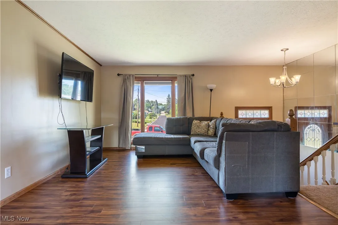 Living area featuring a chandelier, dark wood-type flooring, and a textured ceiling