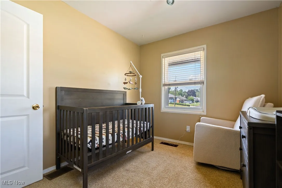 Carpeted bedroom featuring baseboards and a nursery area