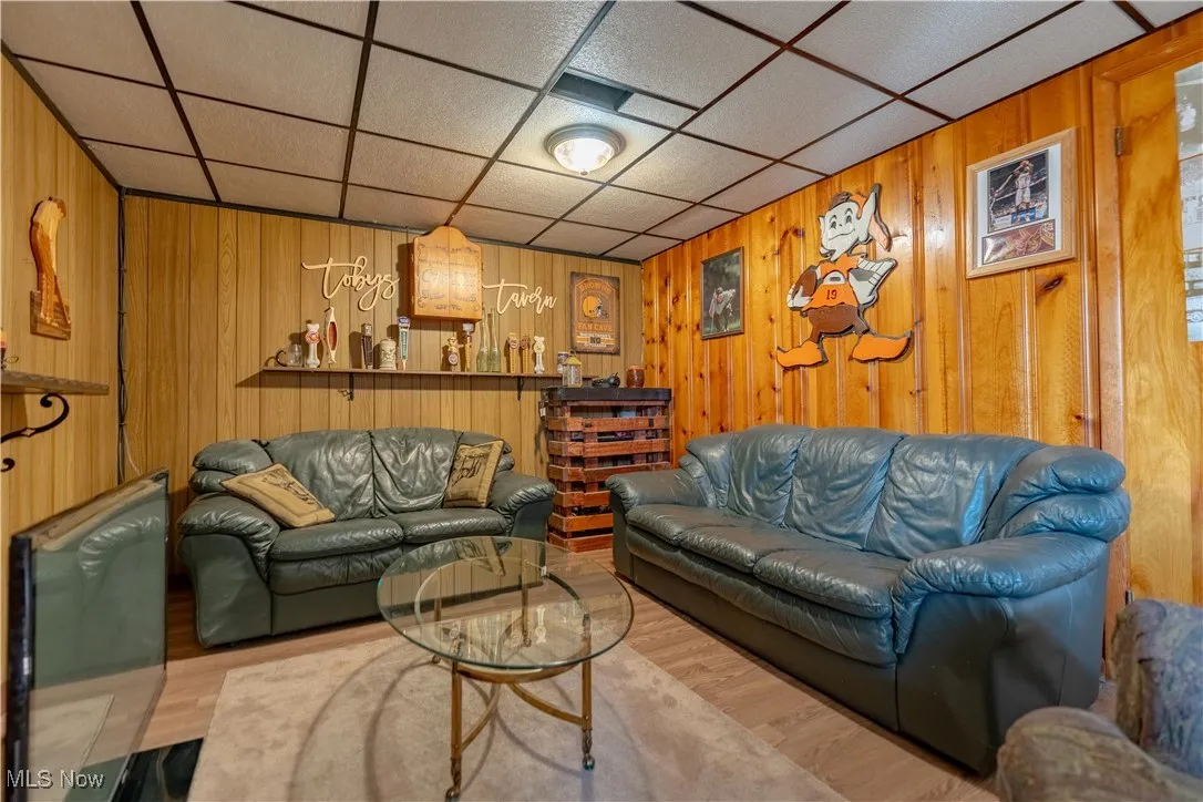Living room with wood walls, wood finished floors, and a paneled ceiling