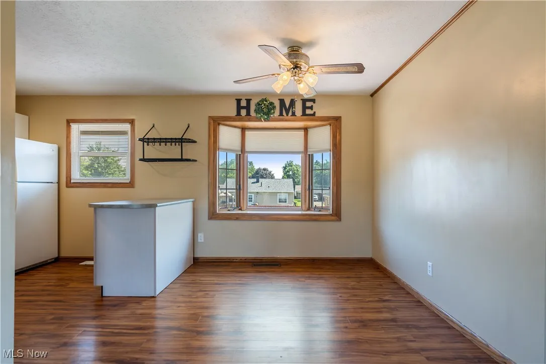 Unfurnished dining area featuring healthy amount of natural light, ceiling fan, and dark wood finished floors