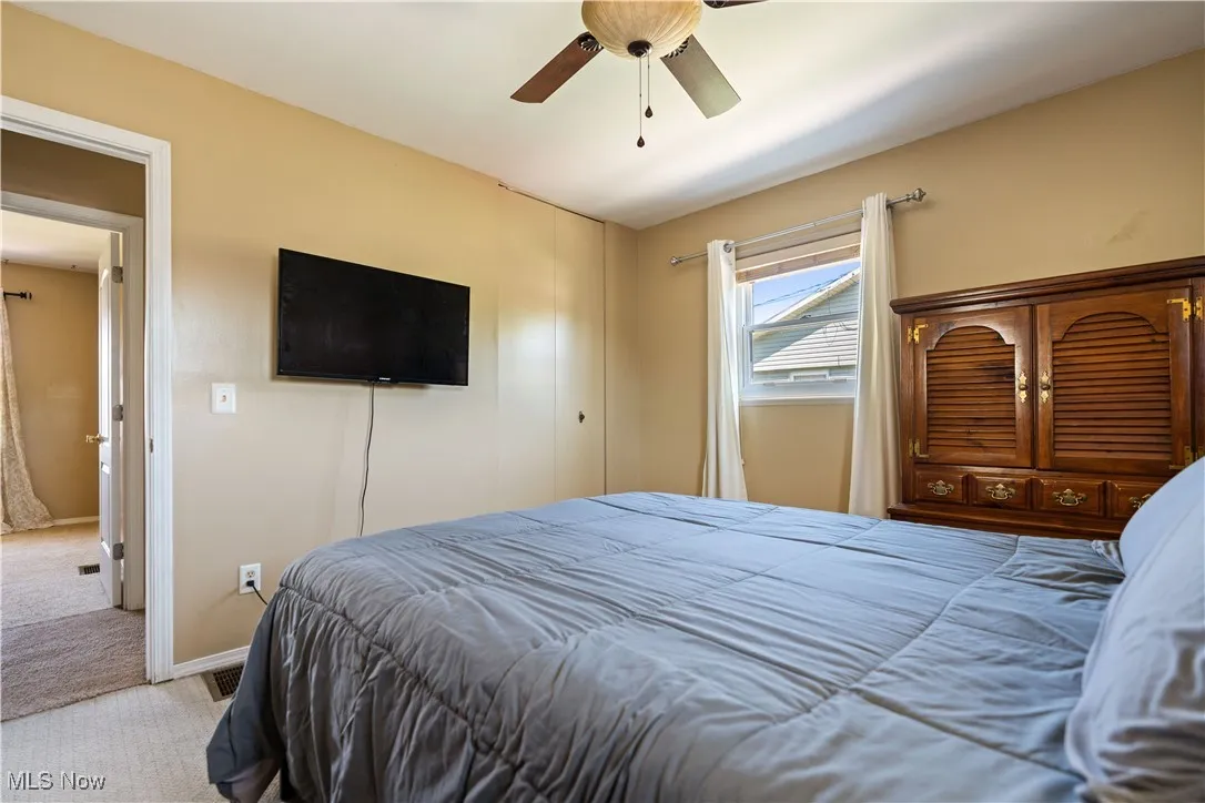 Carpeted bedroom with a ceiling fan and baseboards