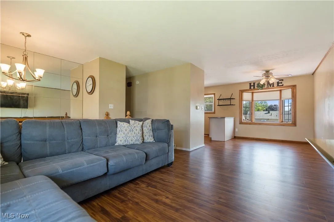 Living room featuring wood finished floors, a chandelier, and a ceiling fan