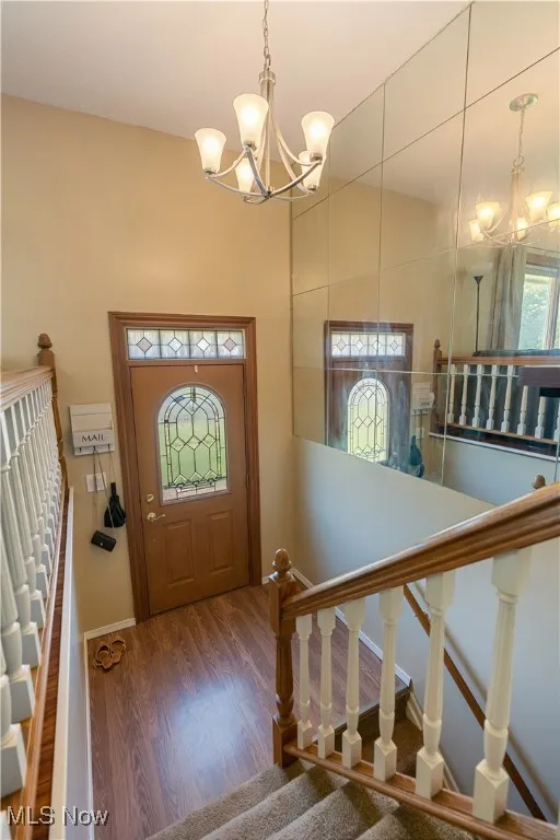 Entrance foyer with a chandelier, wood finished floors, and stairway