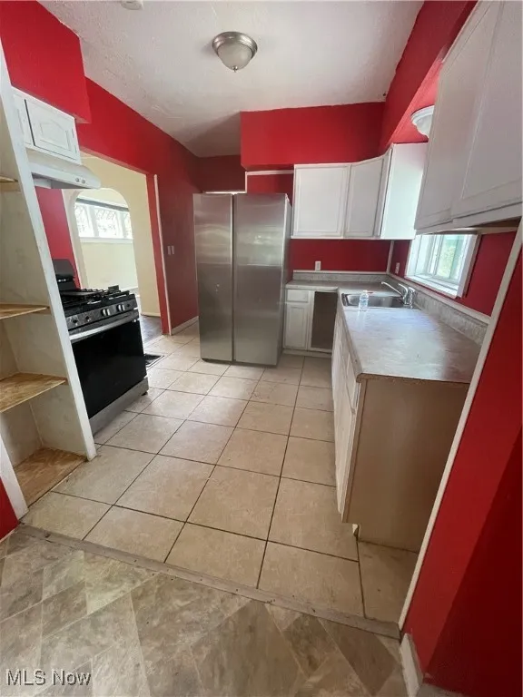 Kitchen featuring white cabinetry, fridge, stove, light countertops, and a textured ceiling