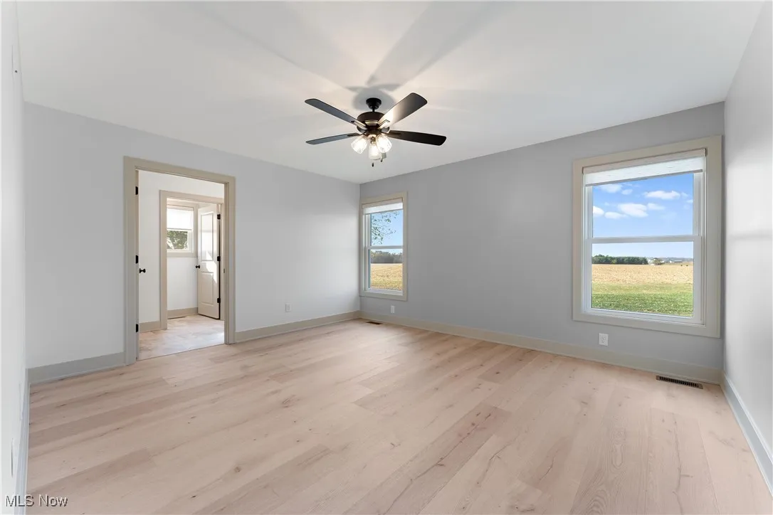 Spare room featuring light wood-type flooring, ceiling fan, and plenty of natural light
