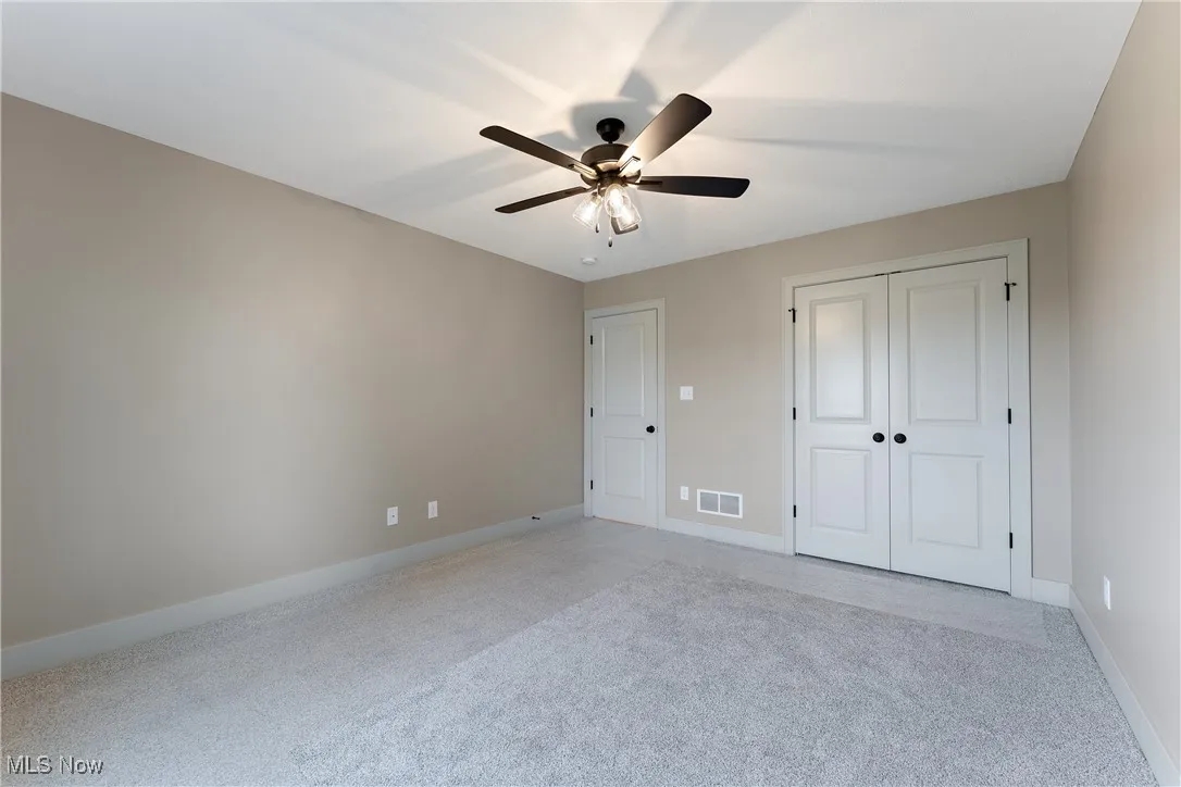 Unfurnished bedroom featuring a closet, light colored carpet, and ceiling fan