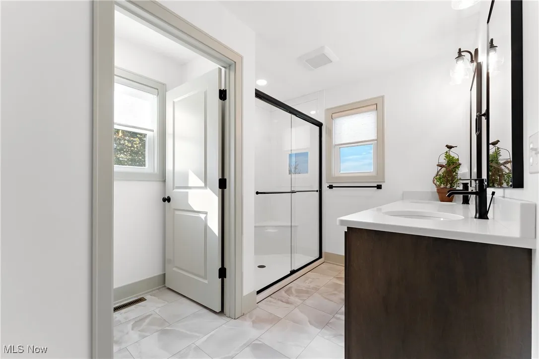 Bathroom featuring a shower with shower door and vanity