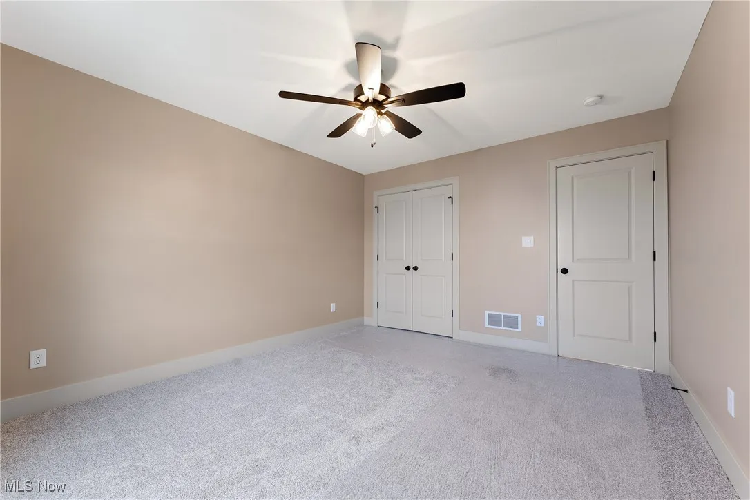 Unfurnished bedroom featuring ceiling fan and light colored carpet