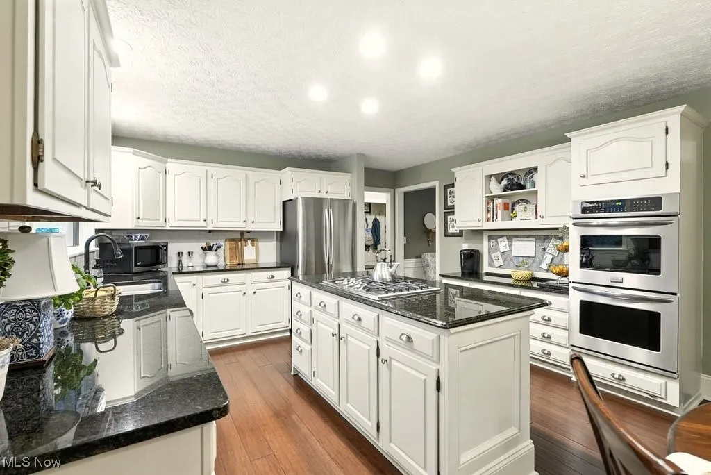 Eat-in Kitchen with Granite Counters, Subway Backsplash, Gas Cooktop, Double Oven, Updated Kitchen Cabinets, Island with a Stove Top, and Extra Wide Baseboards