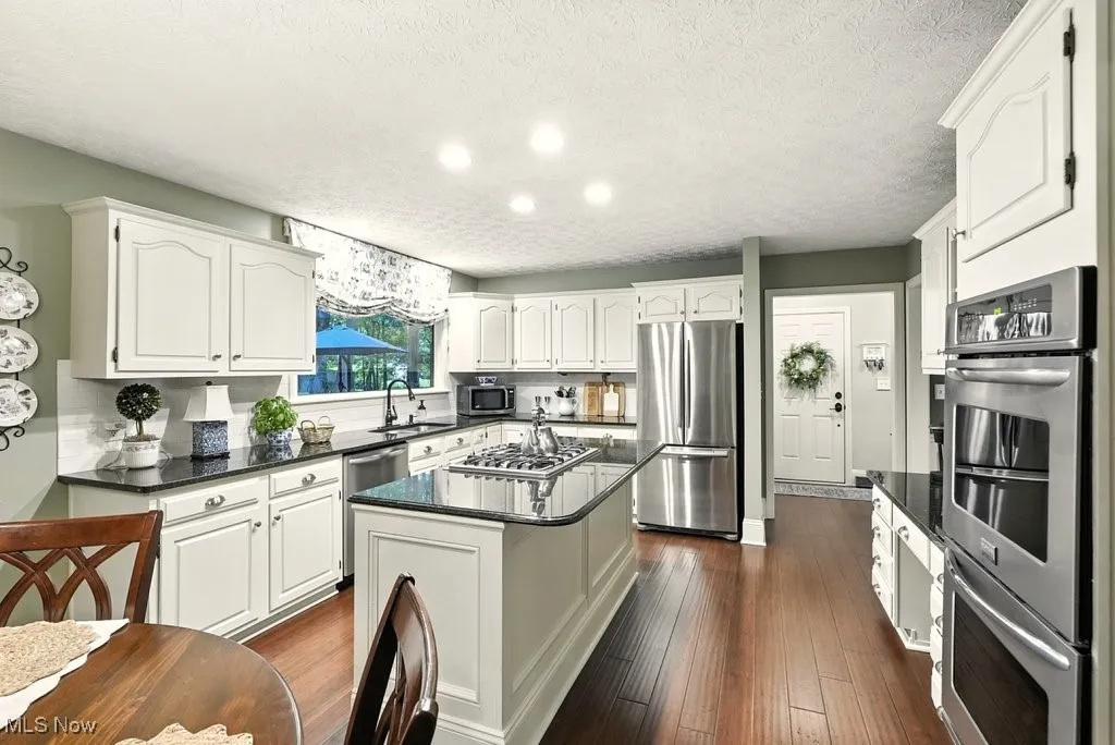 Eat-in Kitchen with Granite Counters, Subway Backsplash, Gas Cooktop, Double Oven, Updated Kitchen Cabinets, Island with a Stove Top, and Extra Wide Baseboards