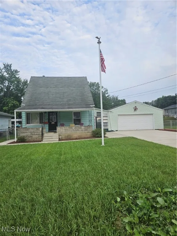 View of front of property featuring a detached garage, covered porch, an outdoor structure, and a shingled roof