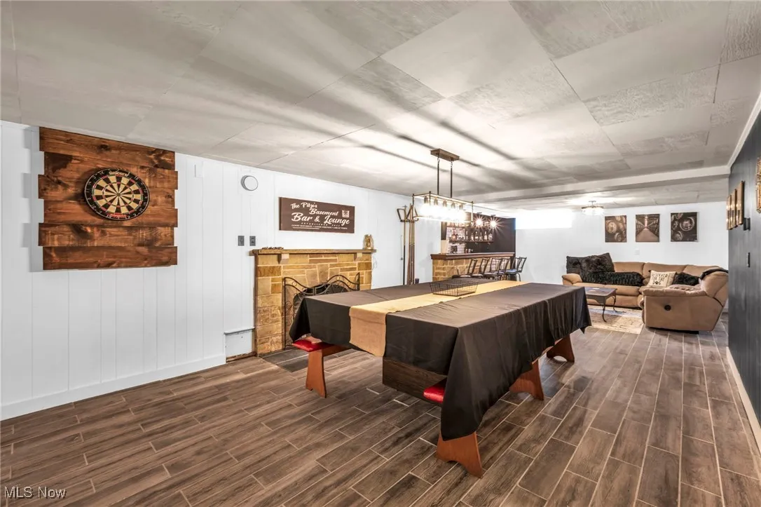 Recreation room with dark wood-style floors and a fireplace
