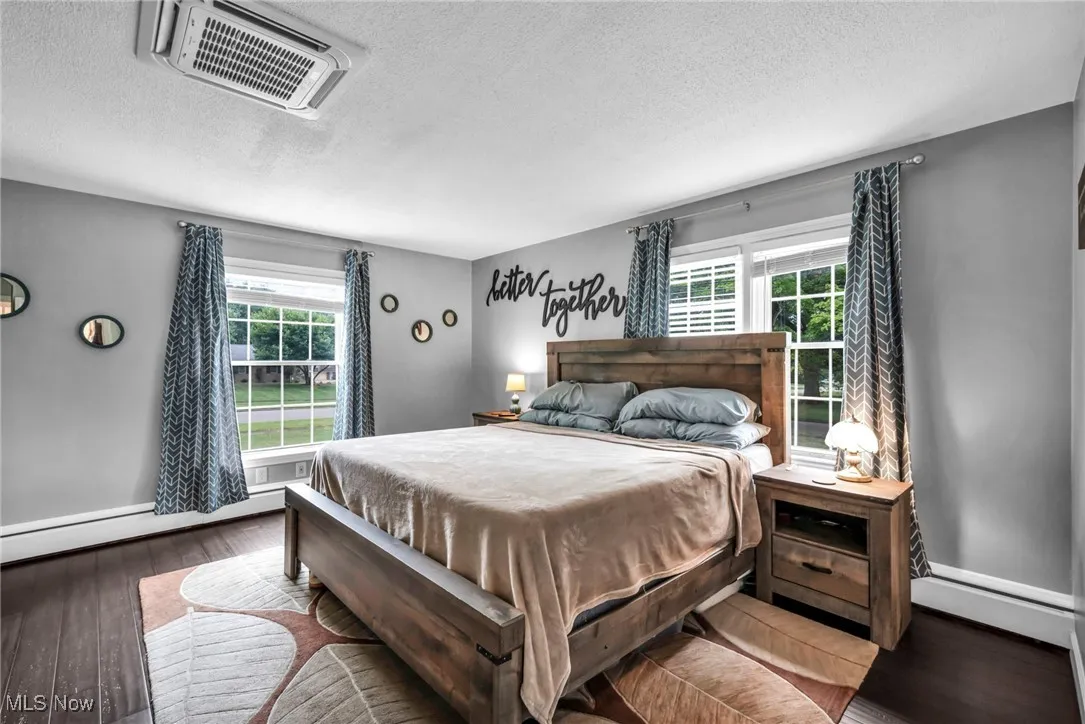 Bedroom featuring a textured ceiling, a baseboard radiator, and wood finished floors