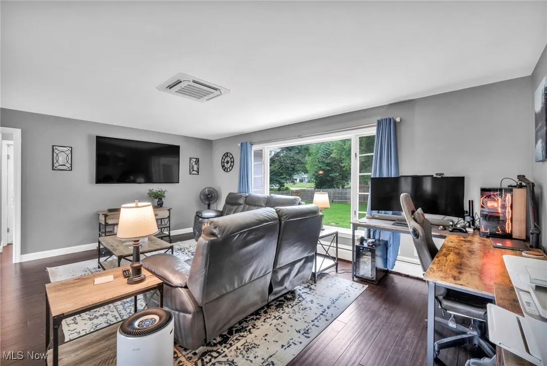 Living area with a desk and dark wood-style floors