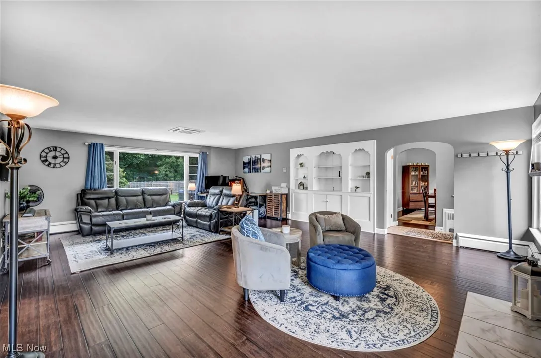 Living area featuring arched walkways, built in shelves, and wood finished floors