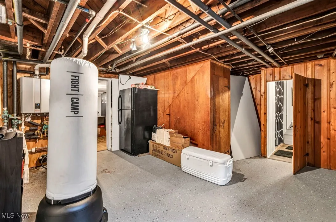 Unfinished below grade area featuring freestanding refrigerator and water heater