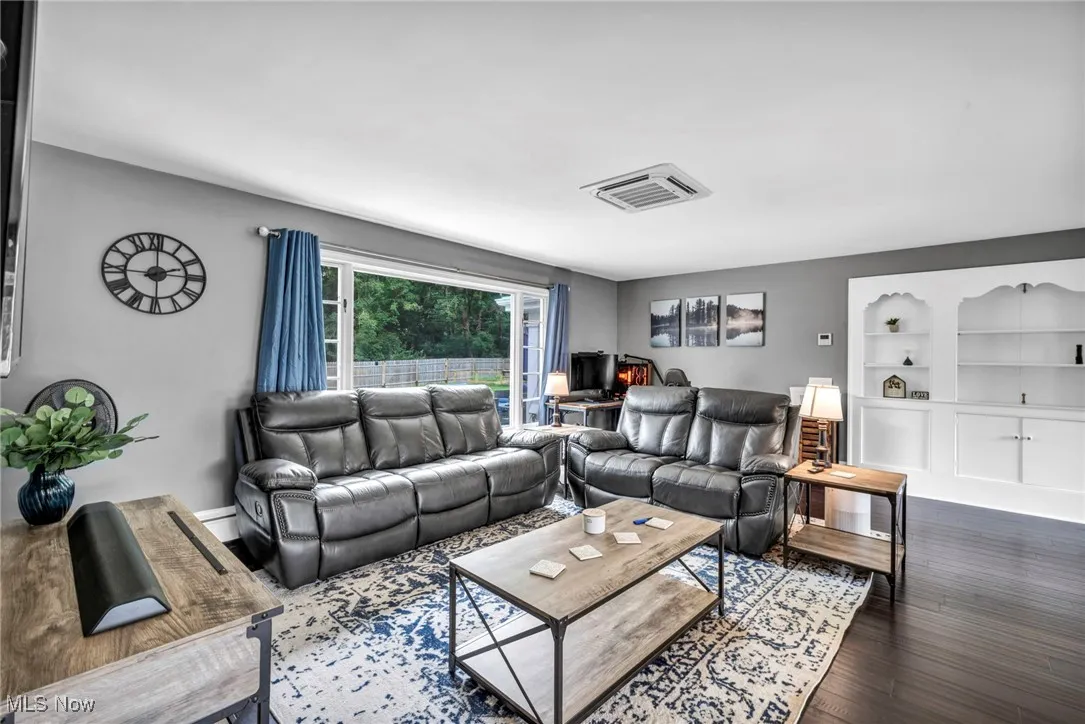 Living room featuring built in shelves and dark wood finished floors