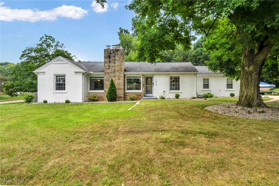 View of front of property featuring a chimney, a front lawn, and brick siding