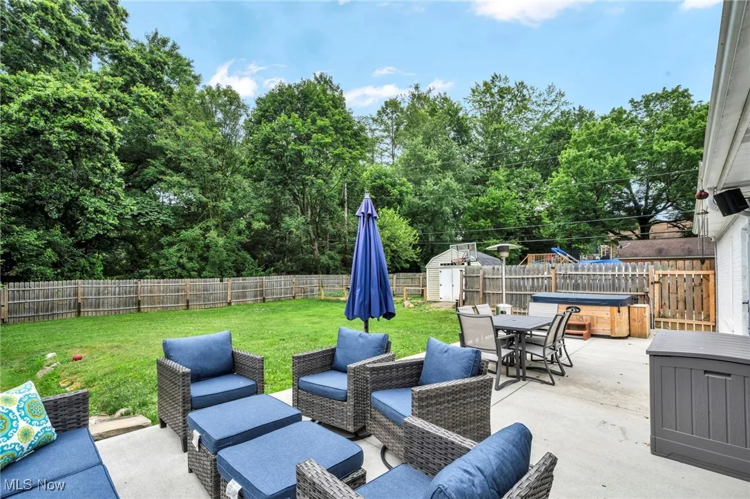 Fenced backyard featuring a patio area, outdoor dining area, a storage shed, a hot tub, and outdoor lounge area