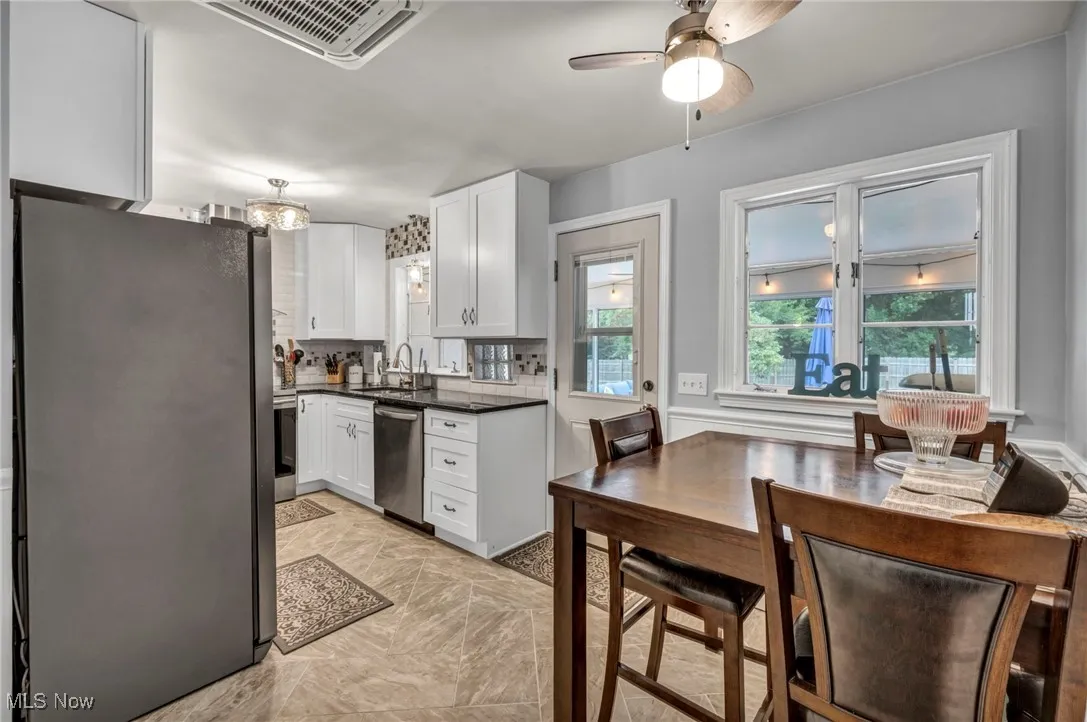 Kitchen featuring stainless steel appliances, white cabinets, dark countertops, and ceiling fan