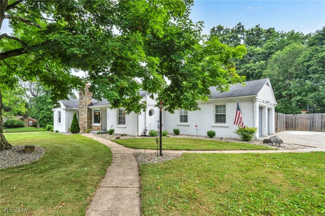 View of front of house featuring concrete driveway, brick siding, a garage, and roof with shingles