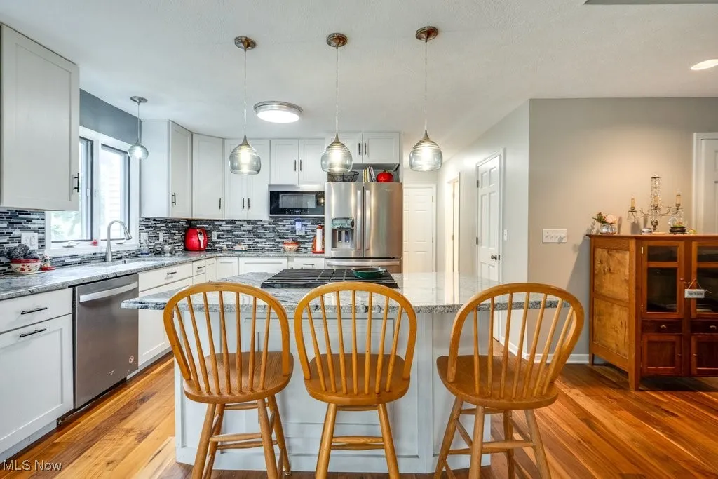 Kitchen featuring appliances with stainless steel finishes, backsplash, and light wood-style flooring
