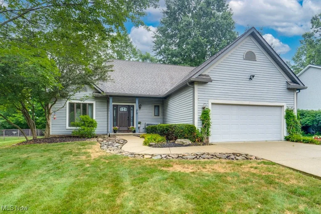 Cape Cod-style home featuring driveway, an attached garage, and a shingled roof