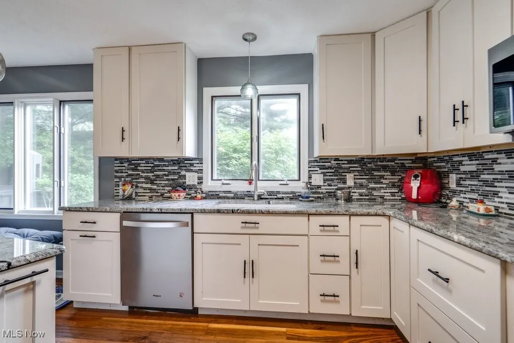 Kitchen with appliances with stainless steel finishes, decorative backsplash, and white cabinets