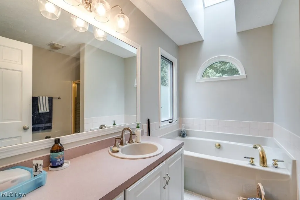 Full bathroom with a garden tub, vanity, and a shower with door