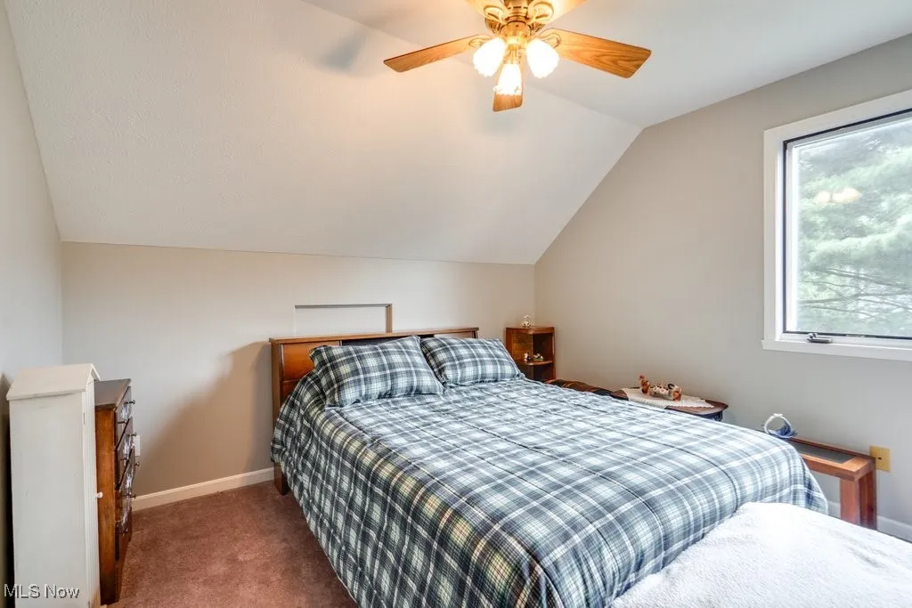 Bedroom featuring vaulted ceiling, carpet flooring, and ceiling fan