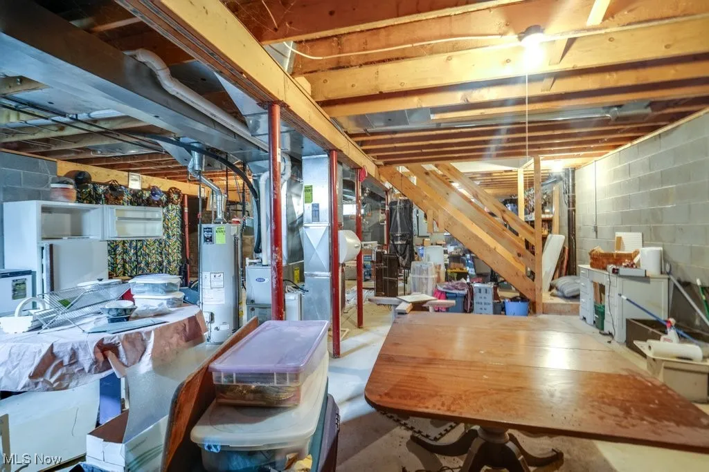 Unfinished below grade area featuring gas water heater and heating unit