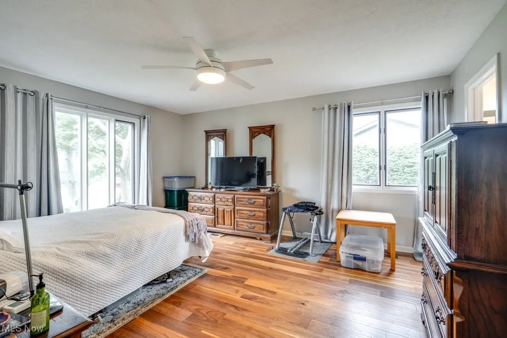 Bedroom featuring multiple windows, light wood-style floors, and ceiling fan