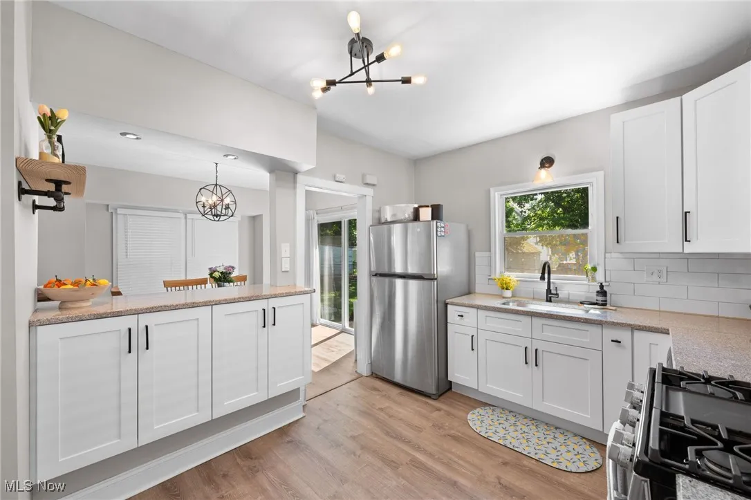 Kitchen with a appliances with stainless steel finishes, light wood-type flooring, and tasteful backsplash