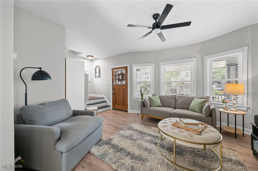 Living area featuring a ceiling fan, light wood-style floors, and stairway