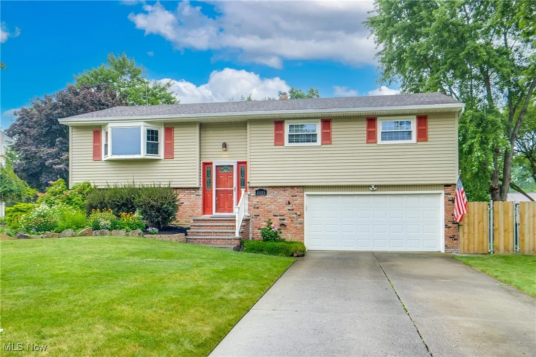 Bi-level home featuring concrete driveway, brick siding, and an attached garage