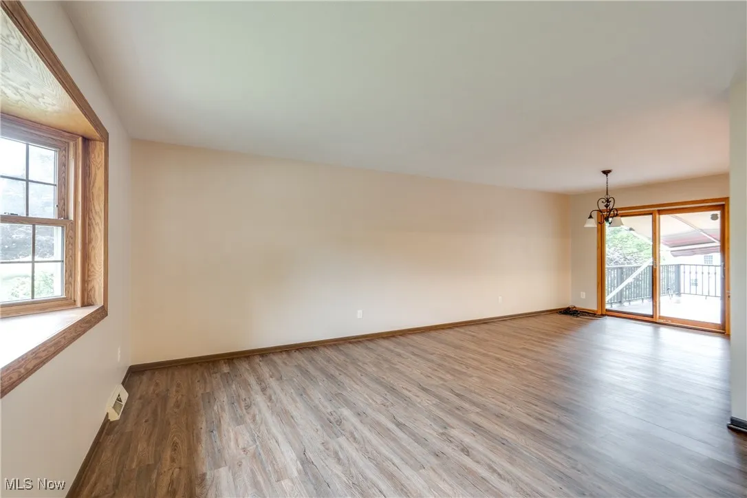 Unfurnished room featuring plenty of natural light, wood finished floors, and a chandelier