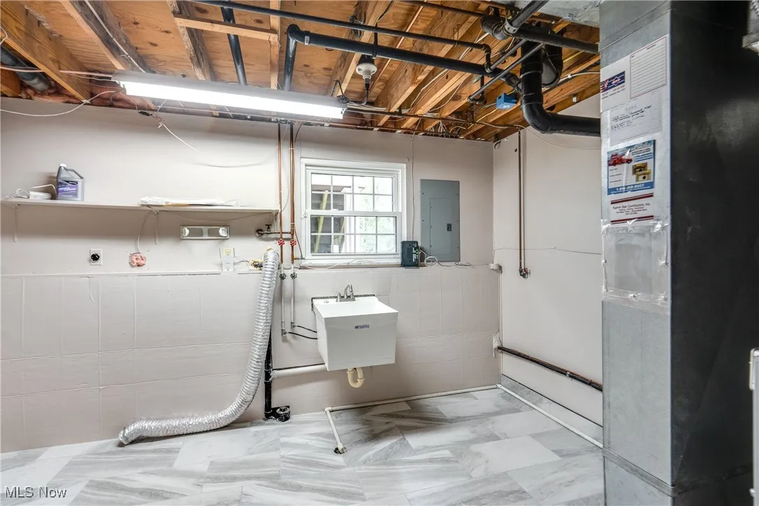 Bathroom with heating unit, tile walls, and electric panel