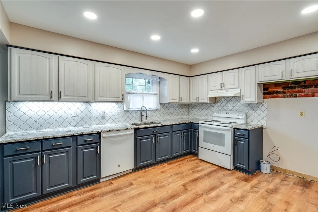 Kitchen featuring white appliances, white cabinetry, light wood-style floors, decorative backsplash, and gray cabinetry