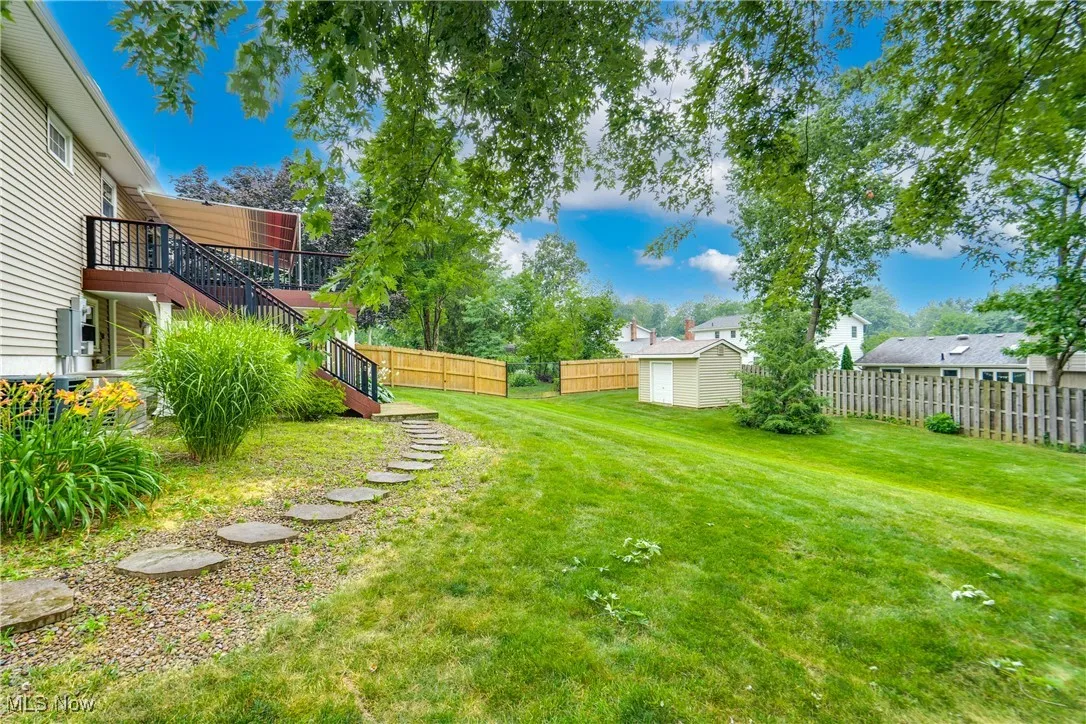 Fenced backyard featuring stairs and a storage unit