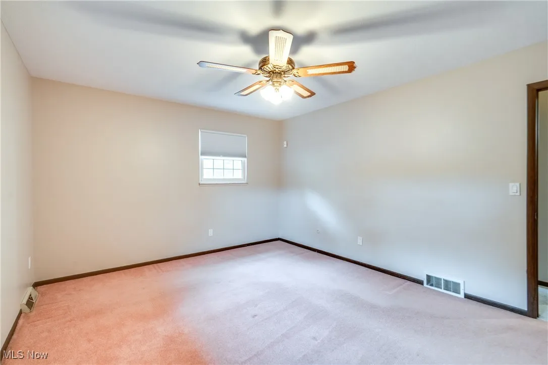 Carpeted spare room with a ceiling fan and baseboards