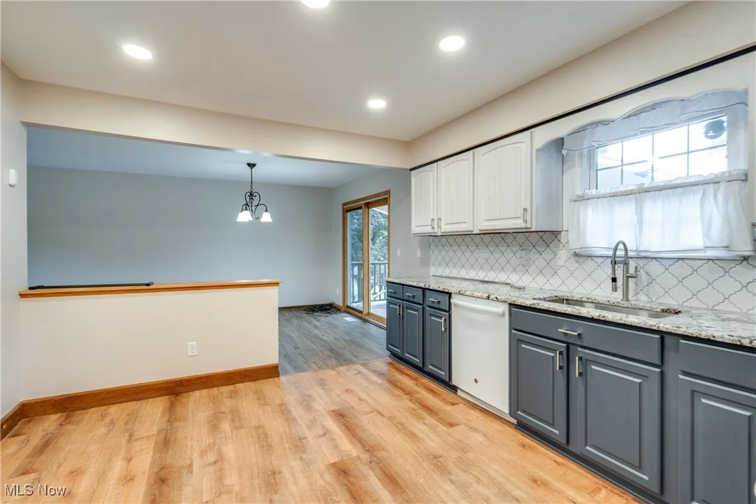 Kitchen with gray cabinetry, a chandelier, tasteful backsplash, light wood finished floors, and recessed lighting