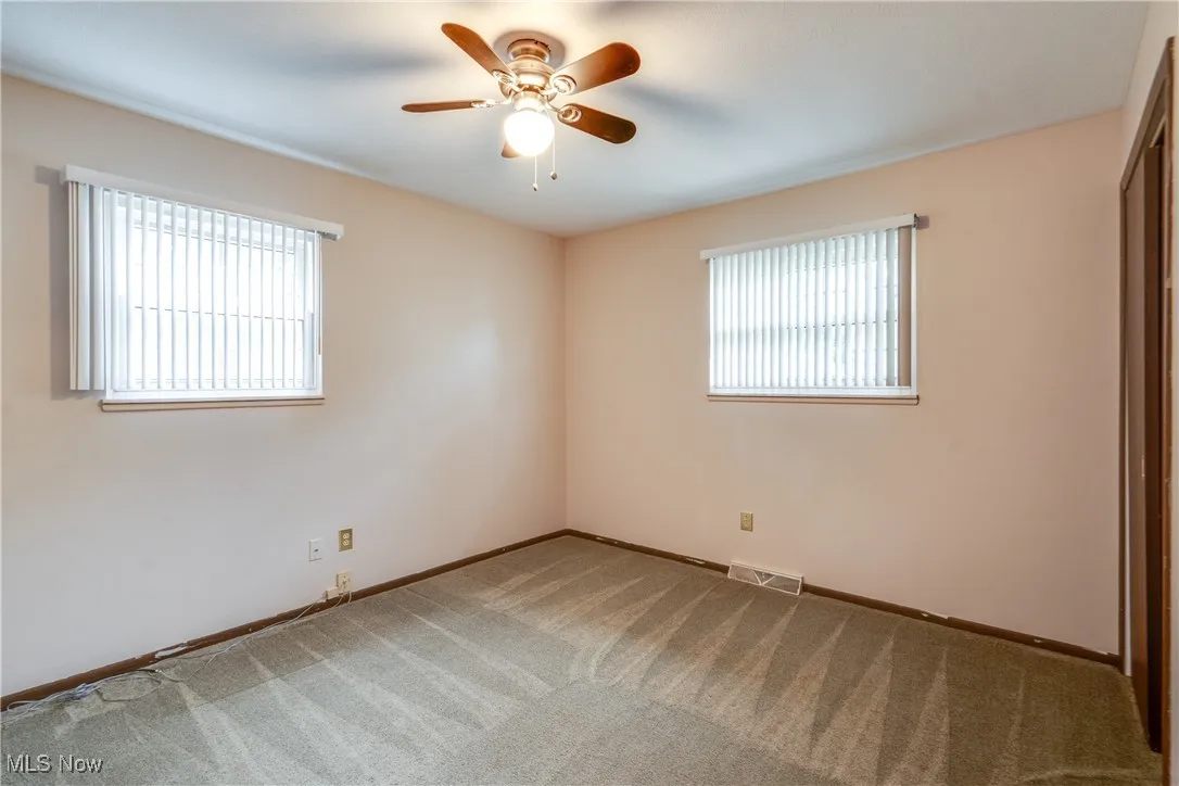 Unfurnished room featuring healthy amount of natural light, carpet, and a ceiling fan