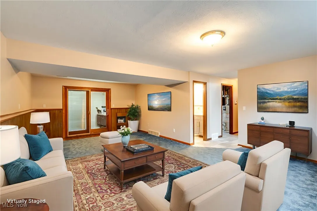 Living room featuring light carpet and a wainscoted wall