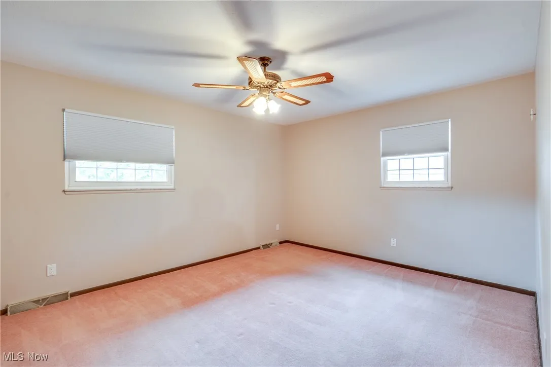 Carpeted spare room featuring a ceiling fan and baseboards